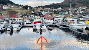 A marina with various boats docked, surrounded by houses and a mountainous backdrop. - 4 Star Holiday Home in Maloy (Kinn)