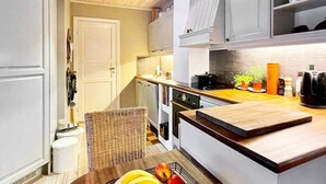 A kitchen with a wooden table, a fruit basket, and a coffee maker. - 4 Star Holiday Home in Maloy (Kinn)