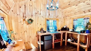 A wooden cabin interior with a kitchen area, including a sink, stove, and dining table.