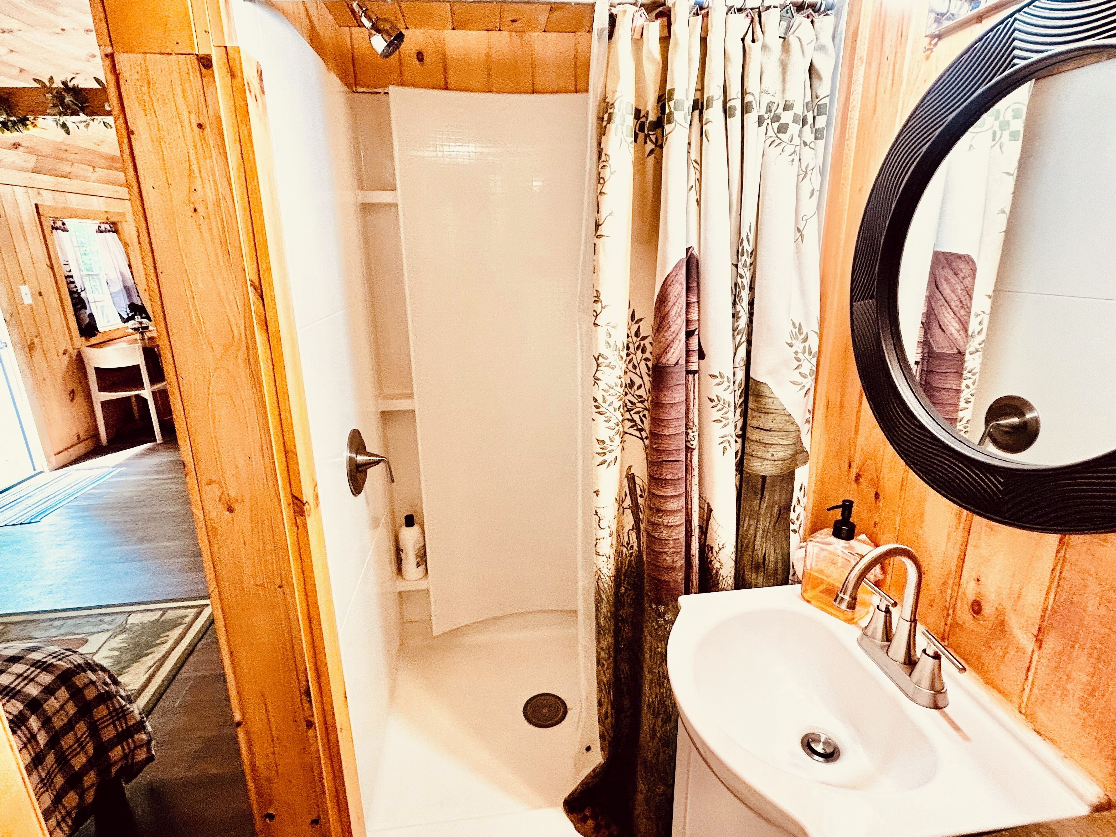 Une salle de bain avec une douche, un lavabo et un miroir.