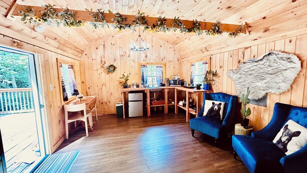 A wooden cabin interior with a dining area, kitchen, and seating.