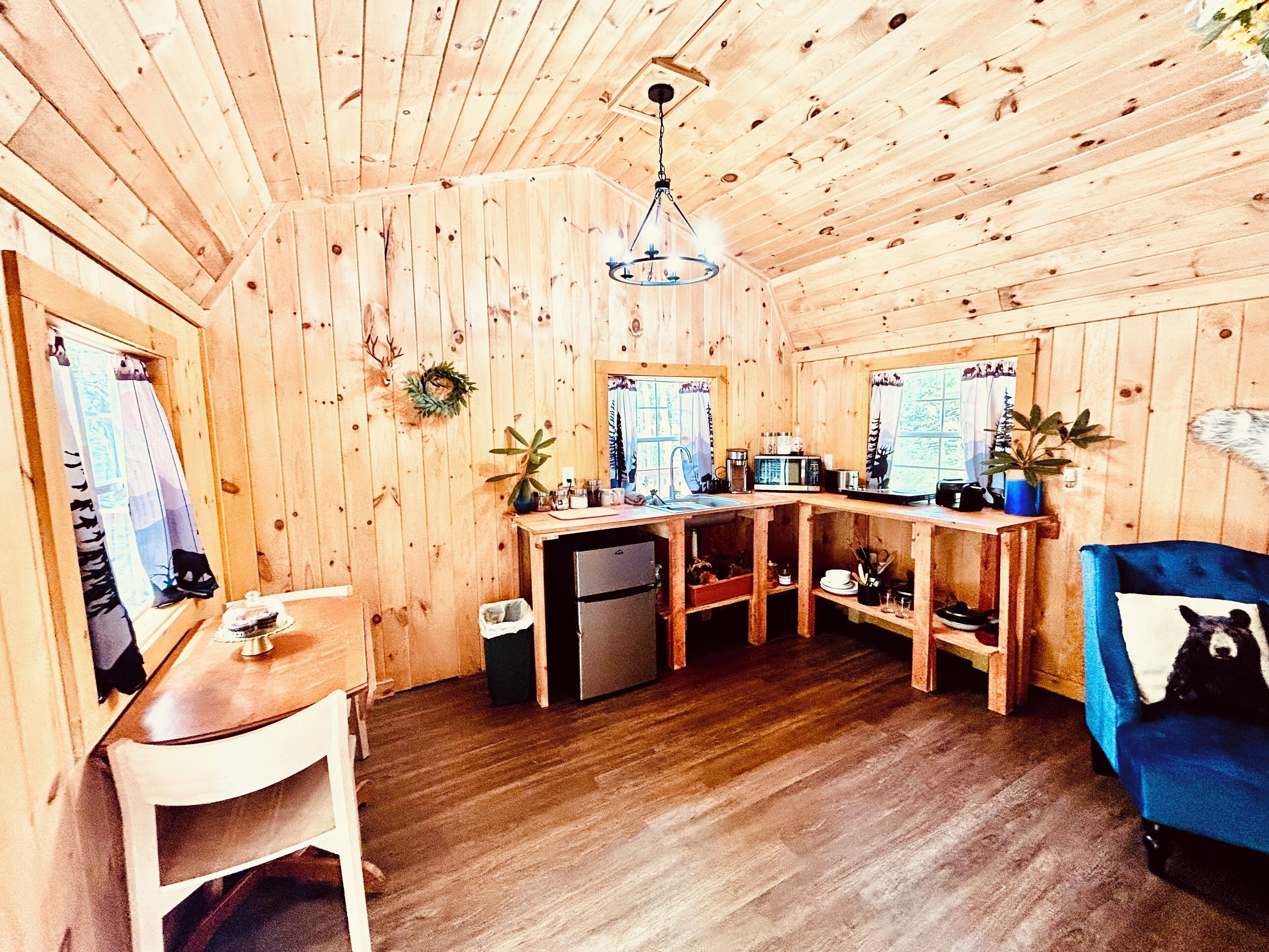 Un intérieur en bois comprenant un coin cuisine, une table à manger et un canapé bleu.