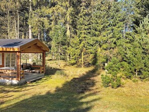 A cabin with a porch, surrounded by dense forest.