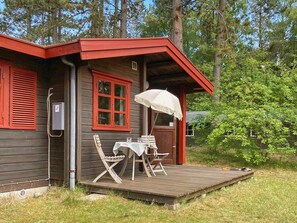 A wooden cabin with a porch, a table, and two chairs. - 4 Person Holiday Home in Store Fuglede (Store Fuglede)