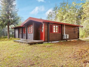 A small cabin with a red roof, a porch, and a single window with shutters. - 4 Person Holiday Home in Store Fuglede (Store Fuglede)