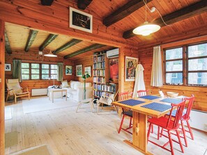 A cozy cabin with a wooden interior, a dining area with red chairs, a bookshelf, and large windows. - 4 Person Holiday Home in Store Fuglede (Store Fuglede)