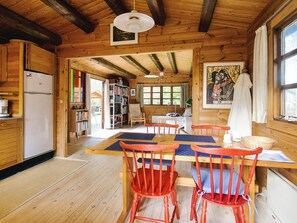 A wooden cabin interior with a dining area, bookshelves, and a refrigerator. - 4 Person Holiday Home in Store Fuglede (Store Fuglede)