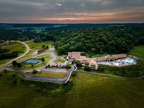 An aerial view of a resort with a swimming pool, tennis courts, and a large building surrounded by greenery. - Valleywood Villa (Galena)