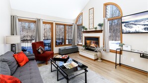 A modern living room with a fireplace, large windows, and a cozy seating area. - Valleywood Villa (Galena)