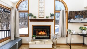 A cozy room with a fireplace, large windows, and a sign reading "Valleywood". - Valleywood Villa (Galena)