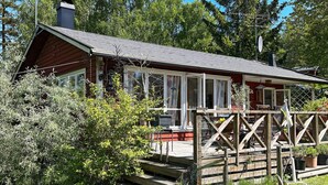 A wooden cabin with a covered porch and a chimney. - 6 Person Holiday Home in Orno (Orno)