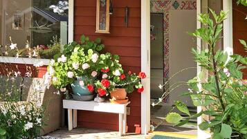 Una casa in legno con un portico, piante in vaso e un lanterna appesa.
