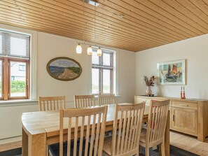 Ein Essbereich mit einem Holztisch und Stühlen, einem Gemälde an der Wand und einem Fenster mit Jalousien.