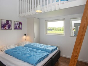 Quarto com cama beliche, janela com vista para área verde e duas pinturas abstratas na parede.