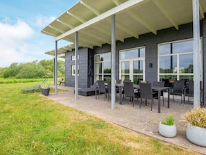 A modern outdoor seating area with a covered patio, large windows, and potted plants. - 10 Person Holiday Home in Haderslev (Årø)
