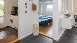 Une chambre à coucher moderne, avec un lit, un bureau et une vue sur un jardin par la fenêtre.