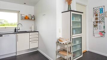A modern kitchen with a built-in dishwasher, a window with a view, and a wall-mounted rack with papers and decorations.