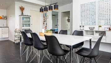 A modern dining area with a white table, black chairs, and pendant lighting.