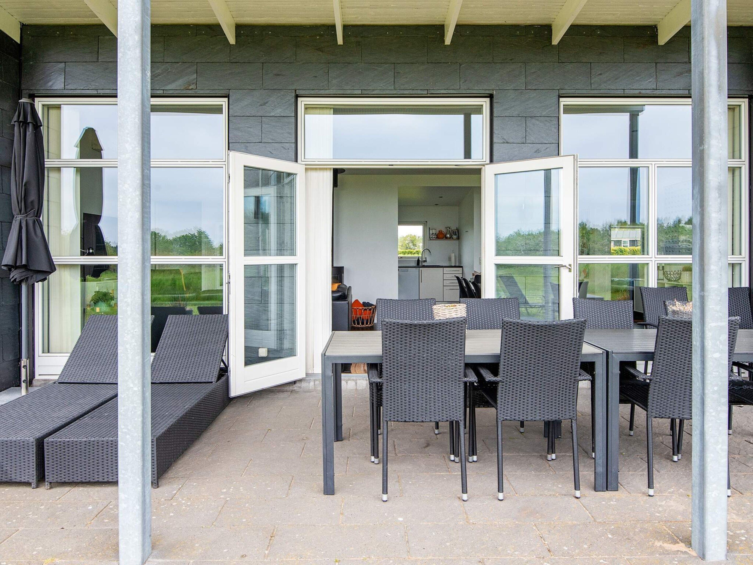 An outdoor dining area with a table and chairs, a covered seating area, and a view of the garden.