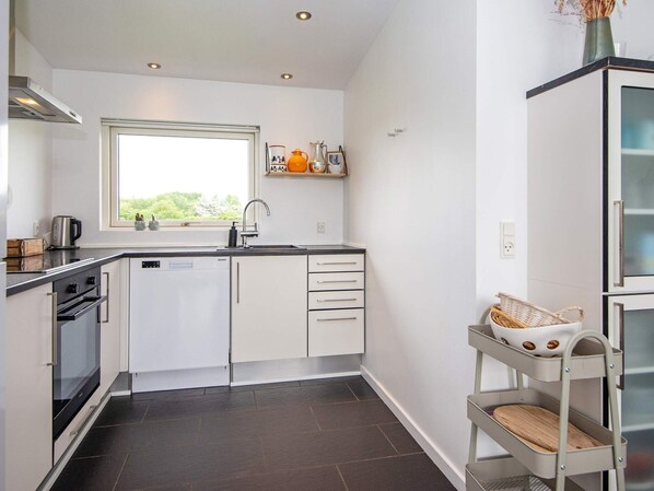 A compact kitchen with a window, built-in oven, and a small sink.