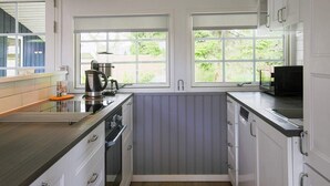 A compact kitchen with white cabinets, a built-in oven, a coffee maker, and a window providing natural light. - 8 Person Holiday Home in Vaeggerlose (Vaeggerlose)