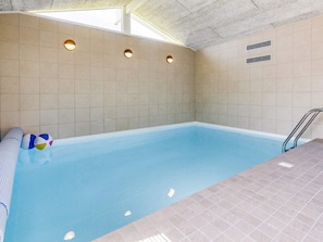A swimming pool with a tiled interior, a metal ladder, and a ceiling with skylights. - 8 Person Holiday Home in Vaeggerlose (Vaeggerlose)