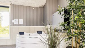 A spa area with a hot tub, a large potted plant, and a wall-mounted information board. - 8 Person Holiday Home in Vaeggerlose (Vaeggerlose)