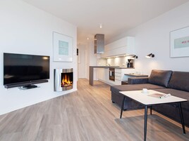 Una sala de estar moderna con una televisión de pantalla plana, chimenea, sofá y mesa de centro.