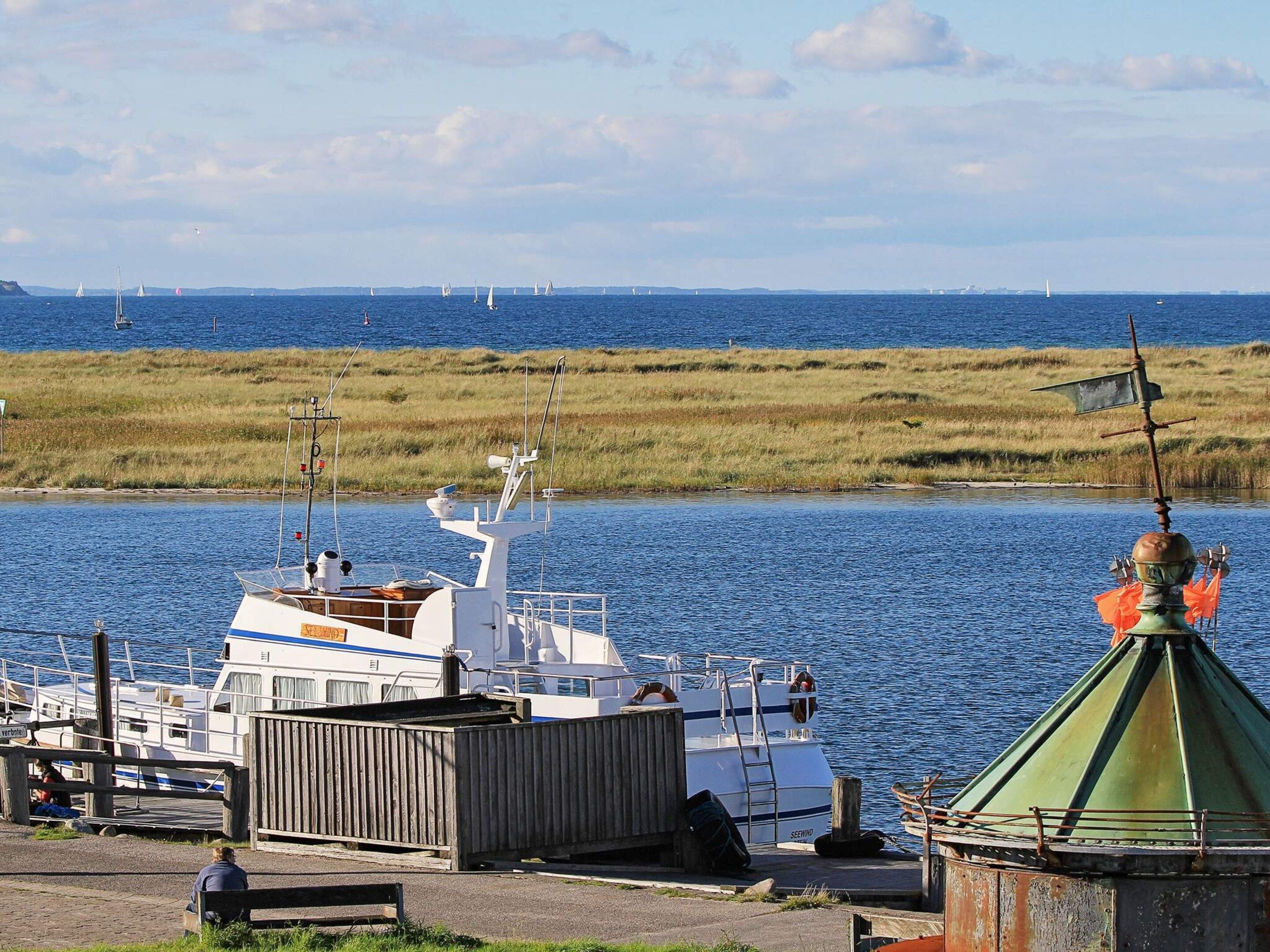 A marina with boats docked, a grassy shoreline, and a clear sky.