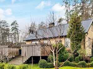 A two-story house with a wooden deck, a chimney, and a well-maintained garden.