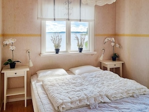 A bedroom with a bed, two bedside tables, a window with a view, and two potted plants. - 6 Person Holiday Home in Saffle (Saffle)