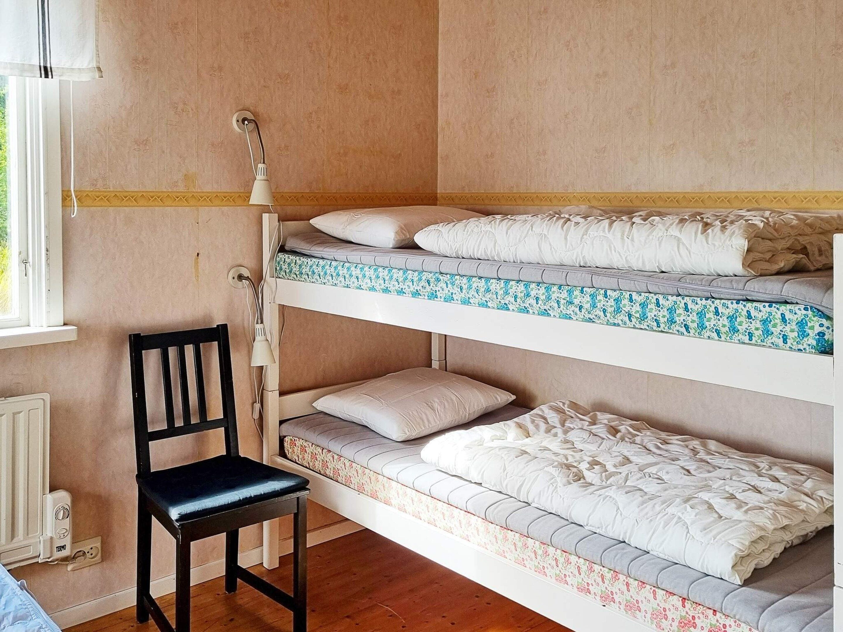 Ein Schlafzimmer mit Etagenbetten, einem Stuhl und einer Lampe.