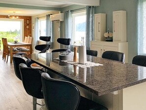 A modern kitchen with a granite countertop, black chairs, and a dining table.