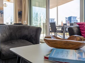 A modern living room with a grey sofa, a white table, and a wooden bowl. - 5 Star Holiday Home in Wendtorf (Wendtorf)