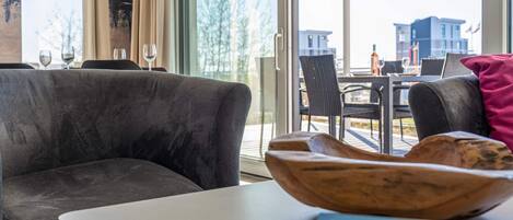A modern living room with a grey sofa, a white table, and a wooden bowl.