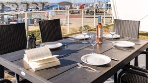 An outdoor dining table with a view of a marina, including boats and a bridge.