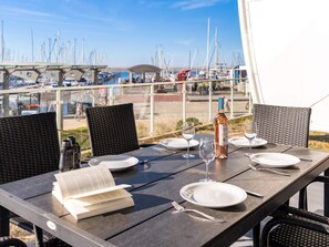 An outdoor dining table with a view of a marina, including boats and a bridge. - 5 Star Holiday Home in Wendtorf (Wendtorf)