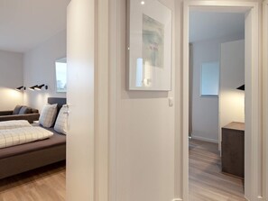 A modern hotel room with a bed, a sofa, a framed picture on the wall, and a door leading to another room. - 5 Star Holiday Home in Wendtorf (Wendtorf)