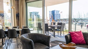 A modern dining area with a view of the marina, including a table with chairs and a sofa. - 5 Star Holiday Home in Wendtorf (Wendtorf)