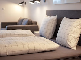 A modern bedroom with a bed, two pillows, a headboard, and a wall-mounted light fixture.