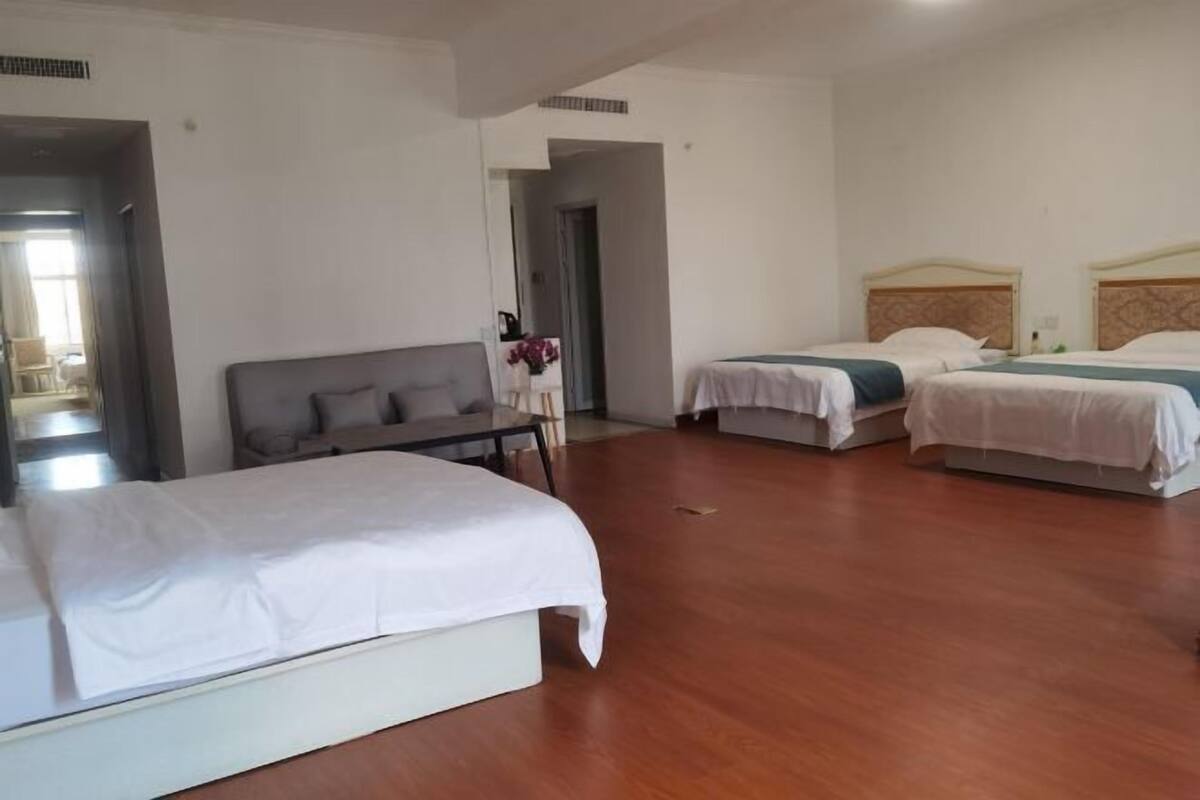Quarto de hotel com duas camas, um sofá e uma mesinha.
