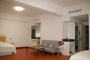 A hotel room with a bed, a sofa, a small table, and a mirror.