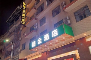 Um edifício de hotel com uma placa verde e outra amarela acima.