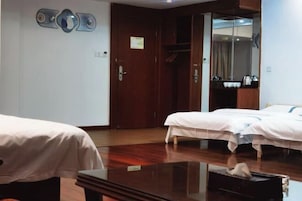 Habitación de hotel con dos camas, piso de madera, un espejo y un perchero.