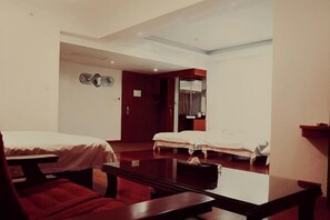 Habitació d'hotel amb dos llits, una taula de fusta i una cadira vermella.