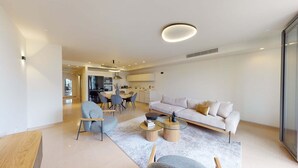 Un salon moderne comprenant un canapé, des fauteuils, une table basse et un coin repas avec une table et des chaises.