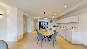 Une cuisine moderne avec des meubles blancs, une table de salle à manger ronde entourée de chaises et une fenêtre bien visible.