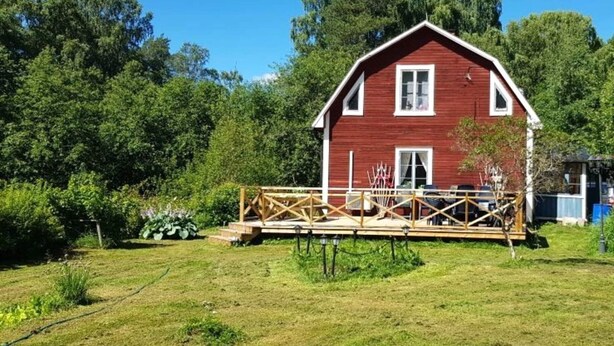 A red barn with a wooden deck and a small porch.