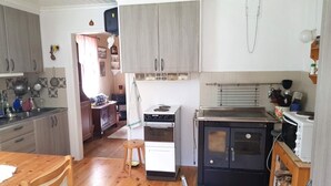 A compact kitchen with wooden cabinets, a stove, and a small dining area with a wooden table and chairs.