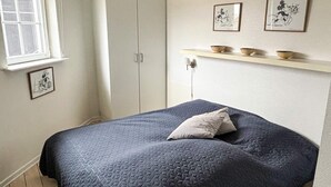 A bedroom with a bed, a wardrobe, a window, and wall-mounted shelves with bowls. - 4 Star Holiday Home in Bogense (Bogense)